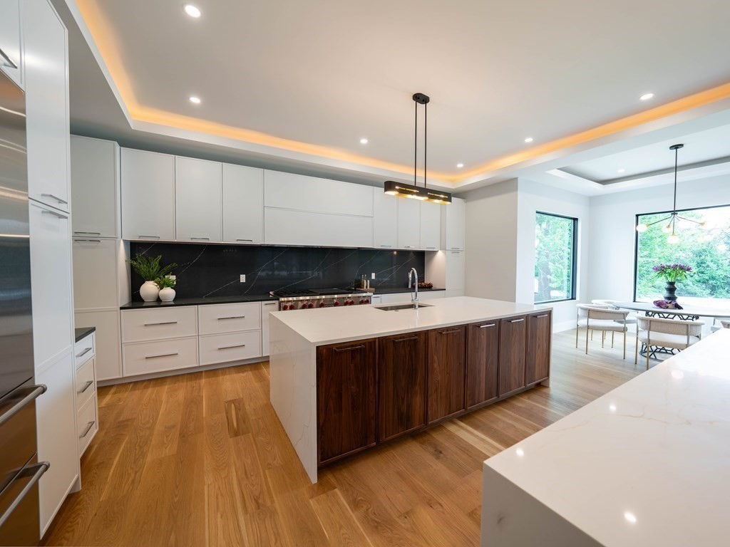 88 Levbert Road Newton, MA 02459 - Photo 10 of 41 a large kitchen with stainless steel appliances a large counter top a stove a chimney a sink and a living room view