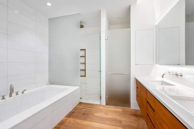 a spacious bathroom with a tub sink and mirror