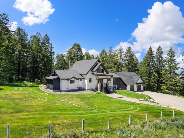 1225 Old Oregon Road Soda Springs, ID 83276 - Photo 58 of 67 Contemporary home exterior featuring white siding and dark trim, a covered entry porch with stone accents, a multi-pitch roofline, an attached garage, and a gravel driveway