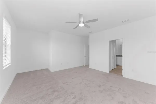 an empty room with a ceiling fan and a window