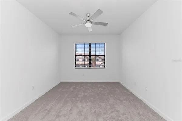 an empty room with a window and a ceiling fan