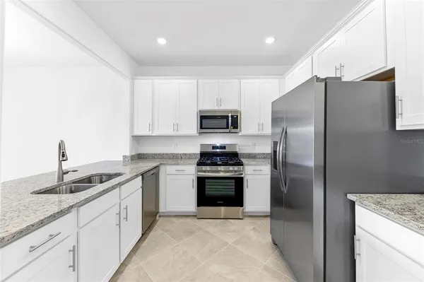 a kitchen with stainless steel appliances granite countertop a refrigerator a sink and a stove