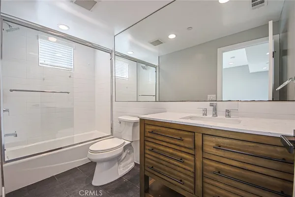 a bathroom with a granite countertop sink toilet a mirror and shower