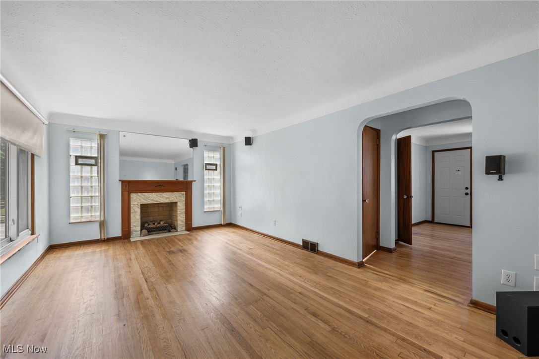 18122 Nottingham Road Cleveland, OH 44119 - Photo 5 of 29 Unfurnished living room with healthy amount of natural light, arched walkways, light wood-type flooring, and a fireplace with flush hearth