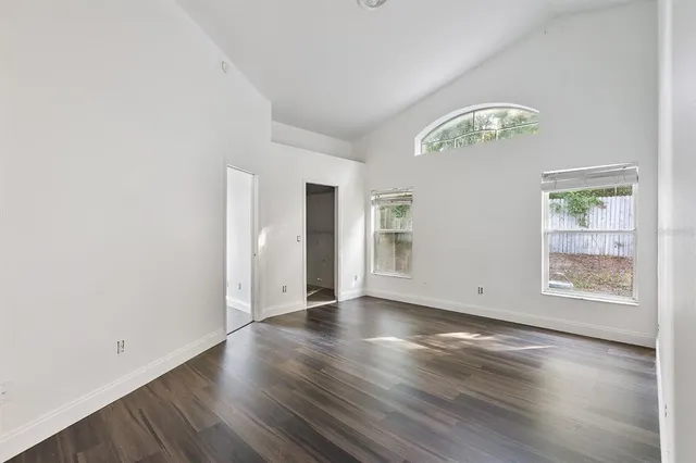 an empty room with wooden floor chandelier and windows