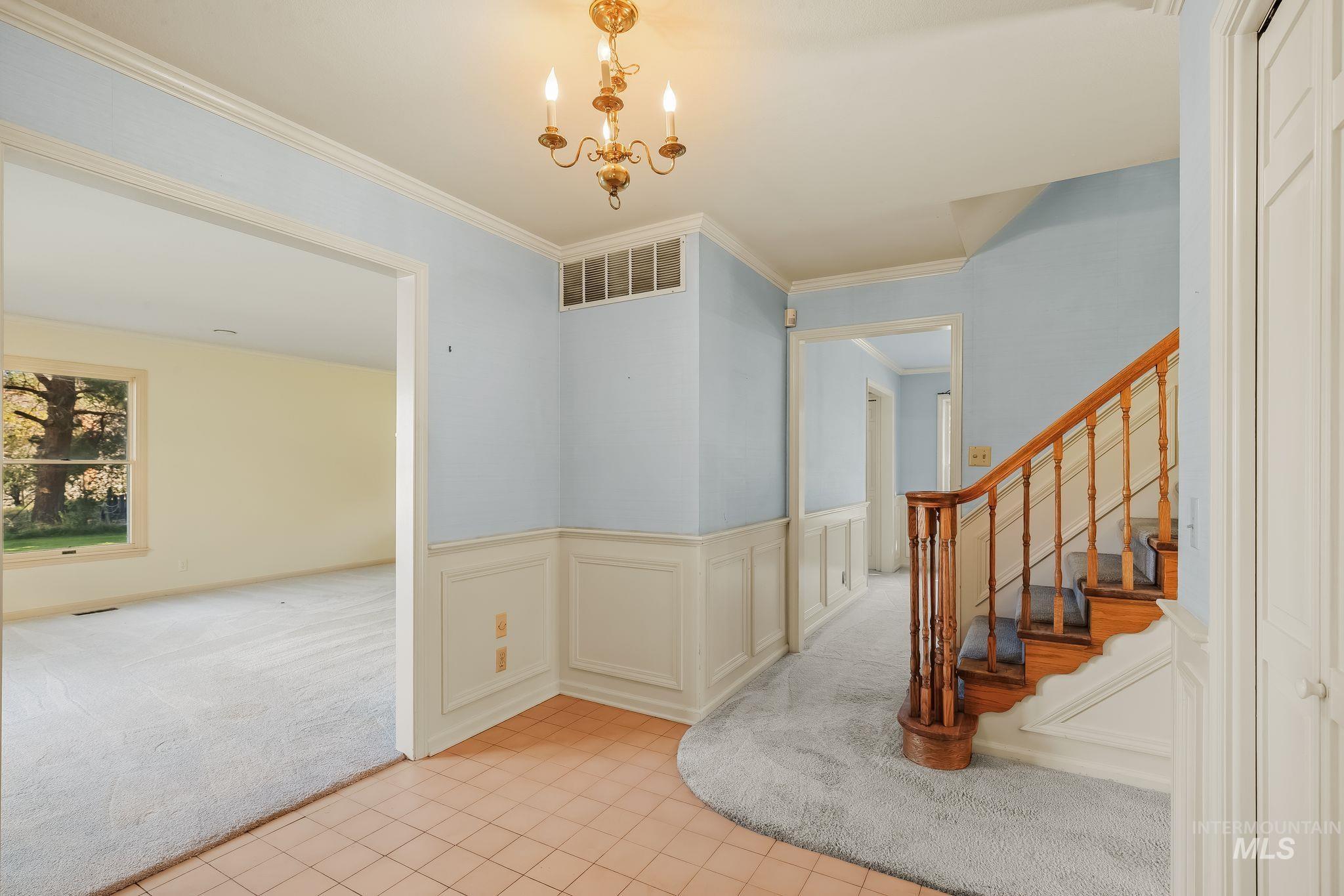 531 Silcott Road Clarkston, WA 99403 - Photo 8 of 43 Entryway featuring a decorative chandelier, wainscoting, and a carpeted staircase with wood banister