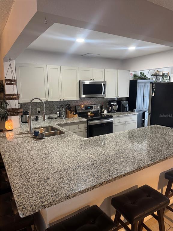 2379 Flamingo Way Winter Park, FL 32792 - Photo 14 of 25 a kitchen with stainless steel appliances granite countertop a table chairs sink and microwave
