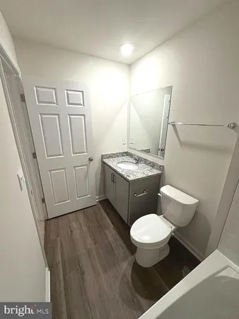 a bathroom with a granite countertop toilet sink and mirror