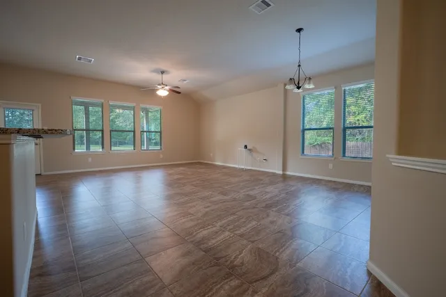 an empty room with wooden floor chandelier and windows