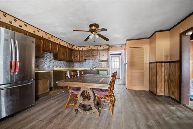 a kitchen with stainless steel appliances granite countertop a refrigerator a sink dishwasher a stove and a dining table with wooden floor