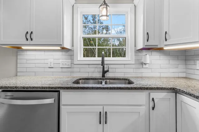 a kitchen with granite countertop white cabinets and a window