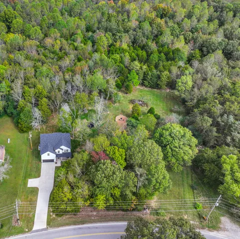 an aerial view of residential house with outdoor space and trees all around