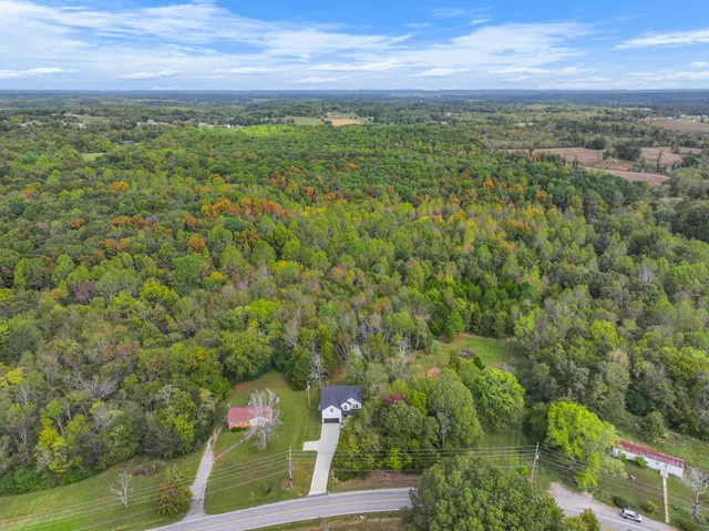 an aerial view of residential house with outdoor space and trees all around