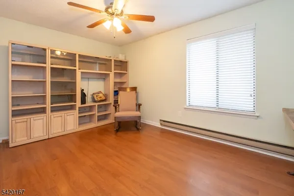 a view of an empty room with a window and wooden floor