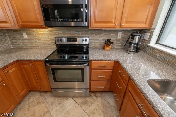 a kitchen with granite countertop a stove top oven microwave and cabinets