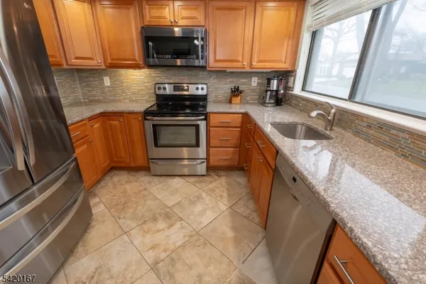 a kitchen with granite countertop a sink a stove top oven a microwave and cabinets