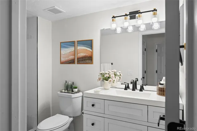 a bathroom with a sink vanity granite toilet and a mirror