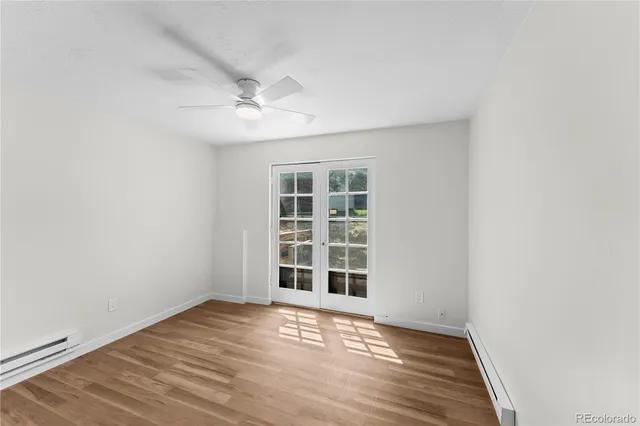 an empty room with wooden floor cabinet and windows