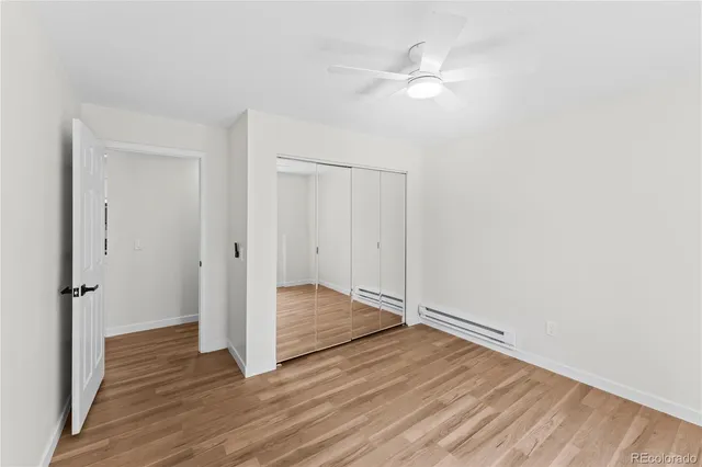 an empty room with wooden floor and ceiling fan