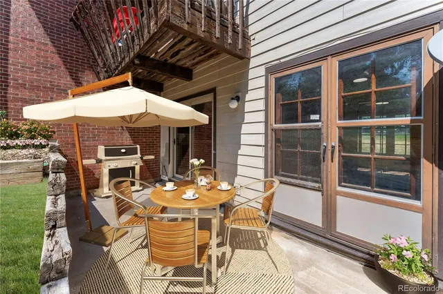 a patio with table and chairs and potted plants
