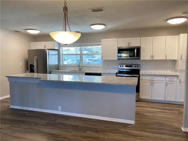 a kitchen with kitchen island a sink stainless steel appliances and cabinets