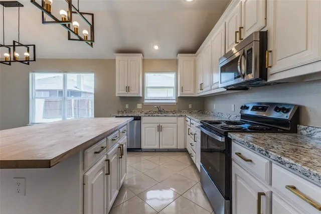 a kitchen with stainless steel appliances granite countertop a stove a sink and a microwave
