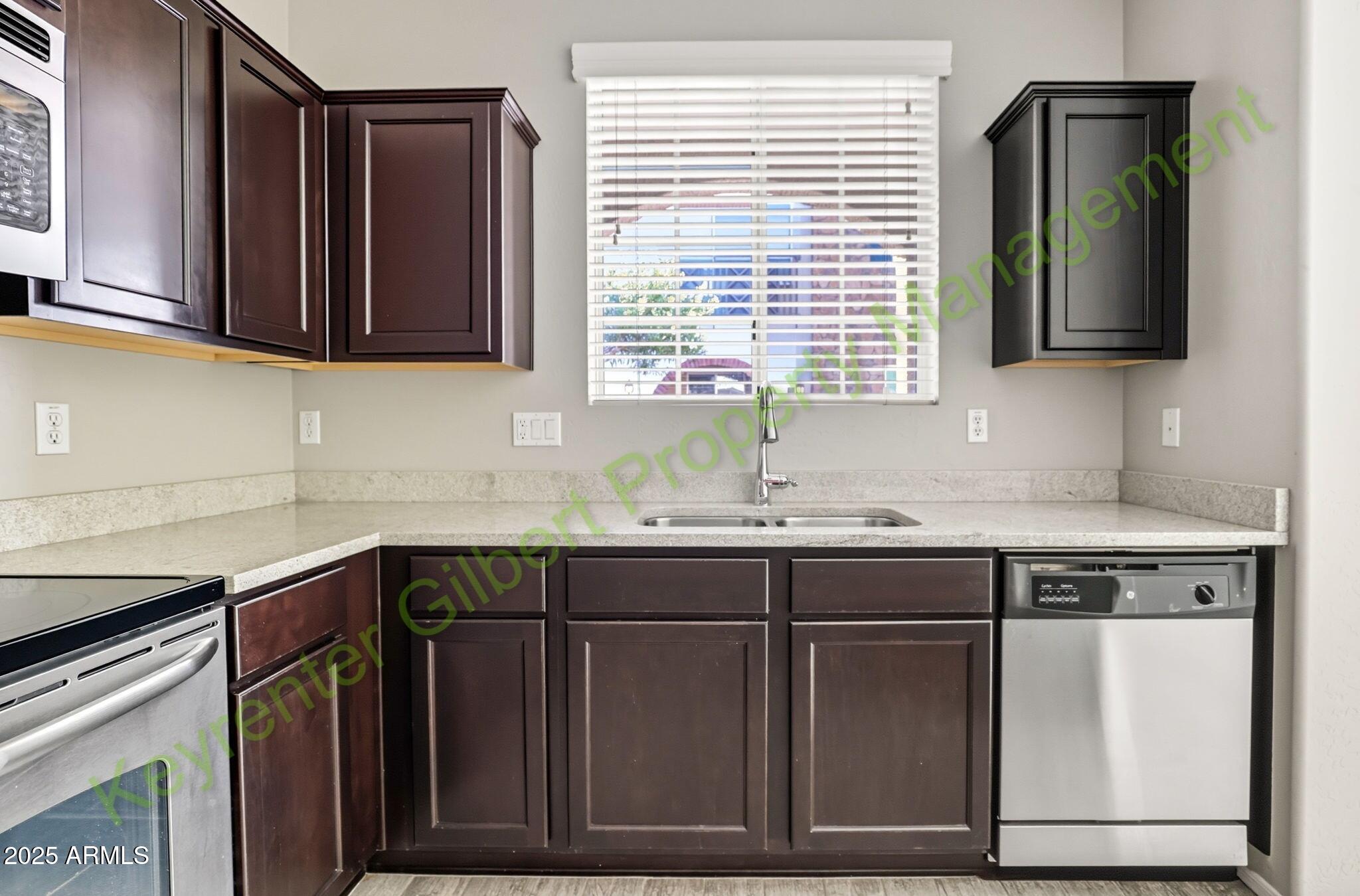 4761 East Portola Valley Drive, Unit 102 Gilbert, AZ 85297 - Photo 9 of 34 a kitchen with stainless steel appliances granite countertop wooden cabinets a sink and a dishwasher