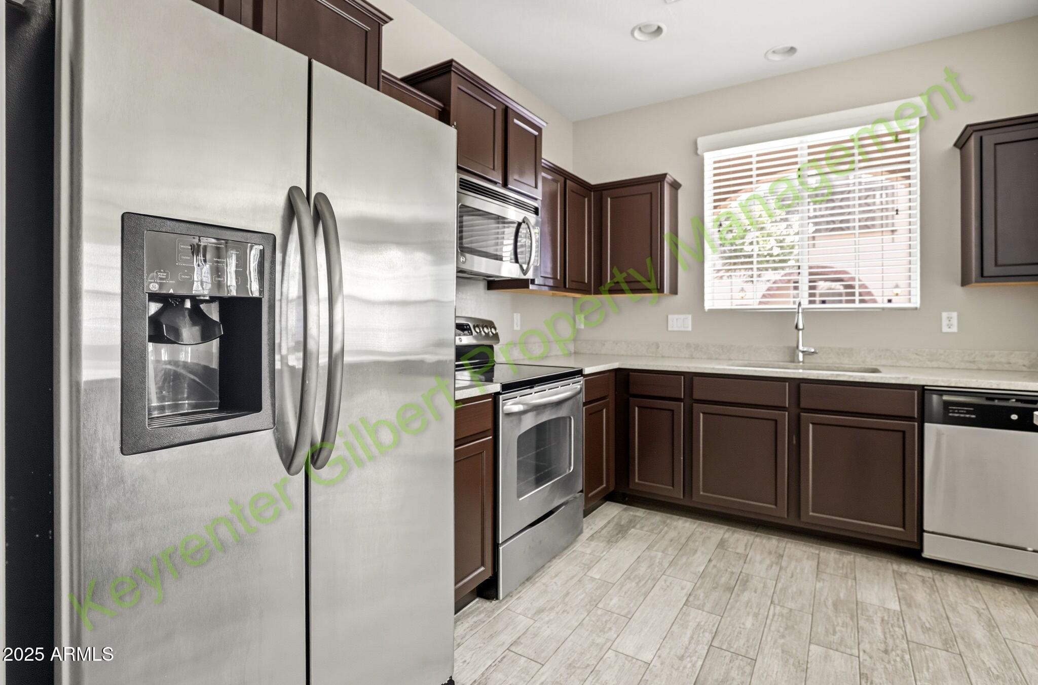 4761 East Portola Valley Drive, Unit 102 Gilbert, AZ 85297 - Photo 10 of 34 a kitchen with stainless steel appliances granite countertop a refrigerator a sink a stove and cabinets