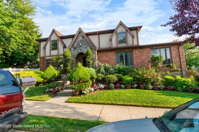 a front view of house and yard with beautiful flowers and green space
