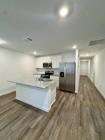 a kitchen with kitchen island granite countertop a sink stove and refrigerator