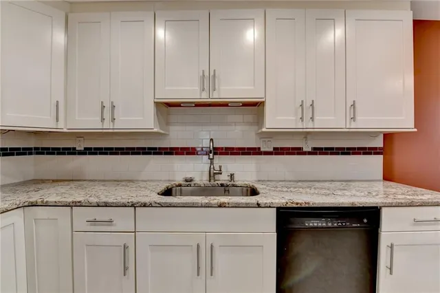 a kitchen with granite countertop white cabinets and sink