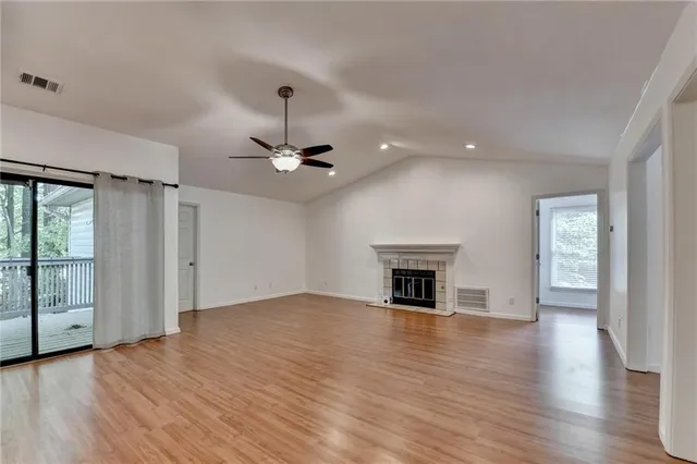 an empty room with wooden floor fireplace and windows