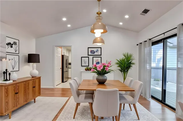 a dining room with wooden floor a chandelier a wooden table and chairs