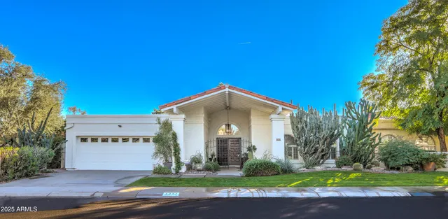 a front view of a house with a garden and trees