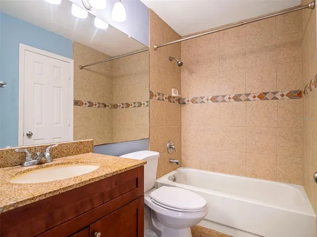 a bathroom with a granite countertop sink a toilet and shower