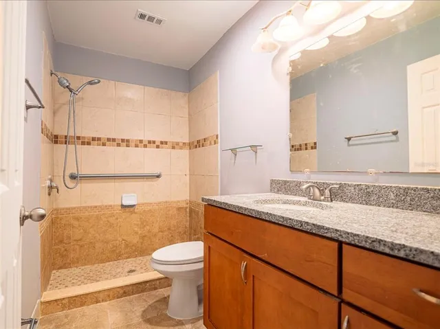 a bathroom with a granite countertop sink a toilet and shower