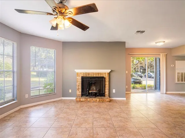 a view of an empty room with window and chandelier fan