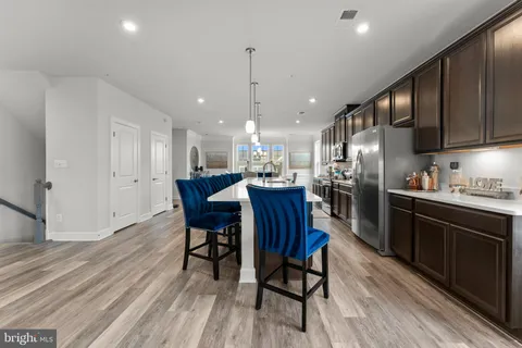 a kitchen with stainless steel appliances granite countertop a dining table chairs stove refrigerator and cabinets