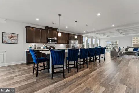a kitchen with stainless steel appliances a dining table chairs and wooden floor