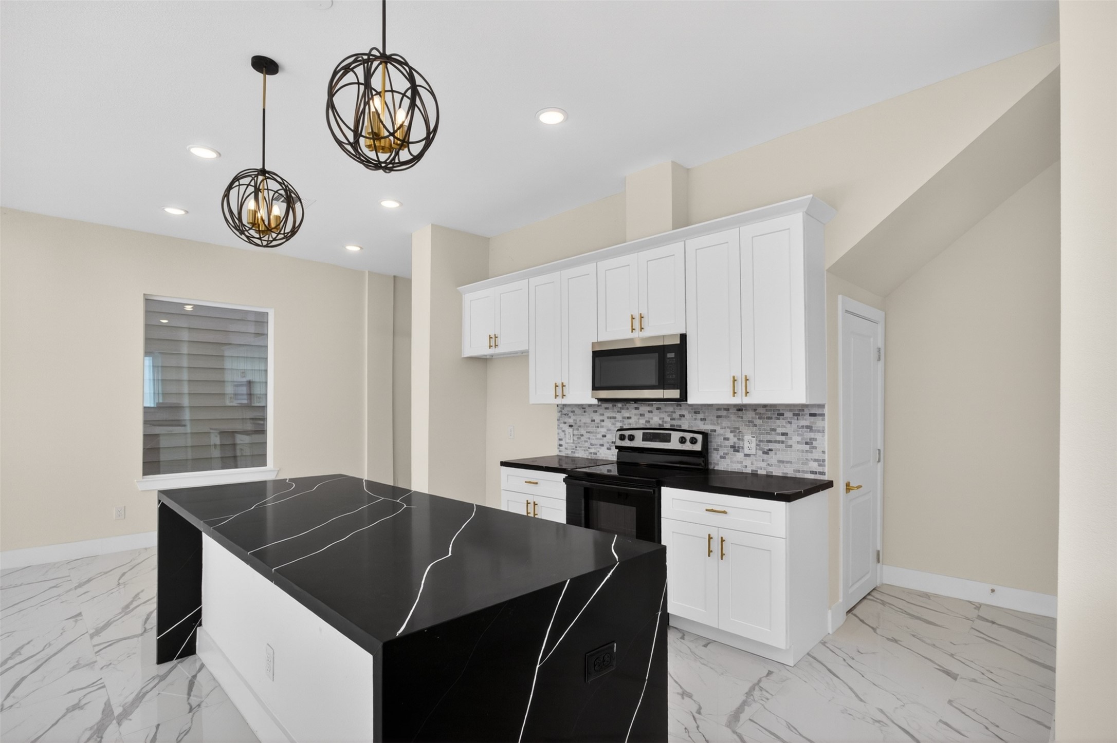 5906 St Augustine Street, Unit F Houston, TX 77021 - Photo 7 of 34 Angled kitchen view highlighting the waterfall island, pendant lighting, stainless appliances, and cabinetry.