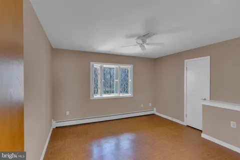 a view of empty room with wooden floor and fan