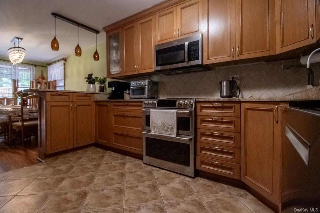 1105 Ulster Heights Road Ellenville, NY 12428 - Photo 25 of 36 Kitchen with stainless steel appliances, kitchen peninsula, hanging light fixtures, backsplash, and light hardwood / wood-style floors