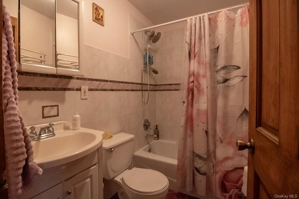 1105 Ulster Heights Road Ellenville, NY 12428 - Photo 26 of 36 Full bathroom featuring vanity, toilet, tile walls, and shower / bath combination with curtain