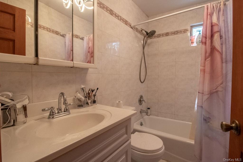 1105 Ulster Heights Road Ellenville, NY 12428 - Photo 34 of 36 Full bathroom with tile walls, shower / bath combination with curtain, toilet, and vanity