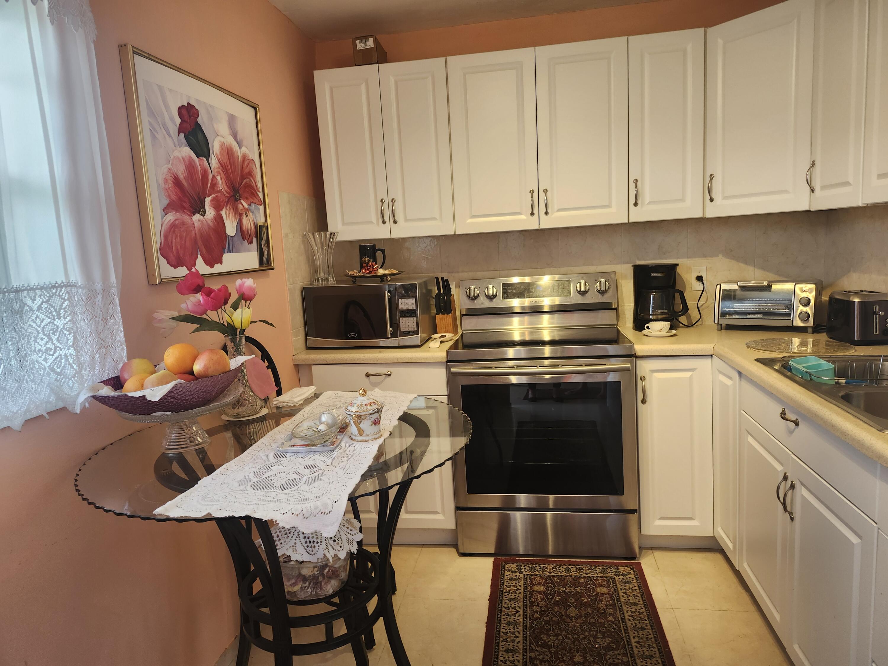 2400 Northeast 1st Lane, Unit 206 Boynton Beach, FL 33435 - Photo 11 of 32 a kitchen with stainless steel appliances granite countertop a stove and white cabinets