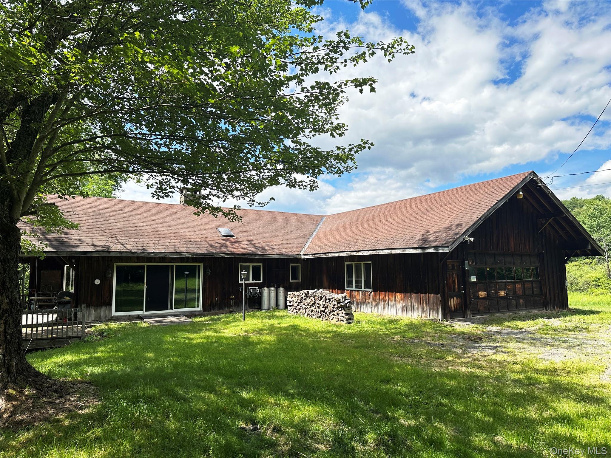 Front exterior featuring rustic western-inspired architecture, expansive attached garage, deck, and natural wooded surroundings.