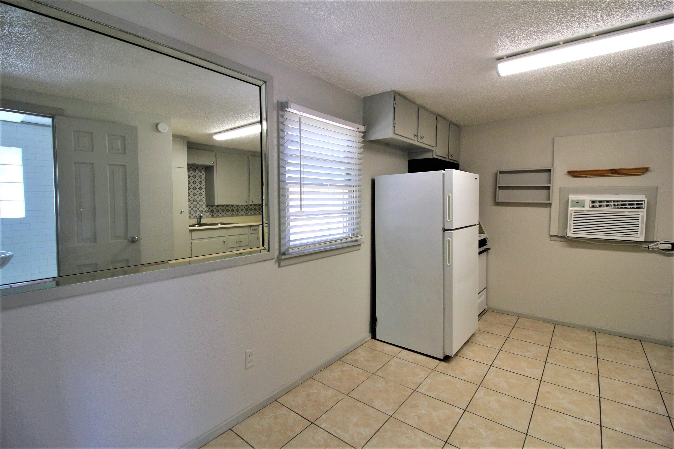 2216 30th Street Lubbock, TX 79411 - Photo 17 of 21 a view of a refrigerator in kitchen and an empty room in wooden floor