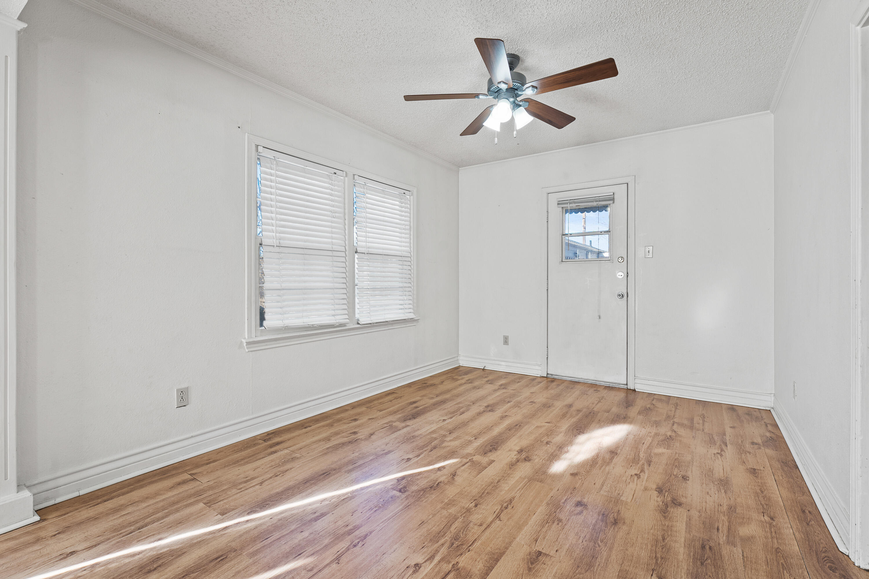 2216 30th Street Lubbock, TX 79411 - Photo 3 of 21 an empty room with wooden floor ceiling fan and window