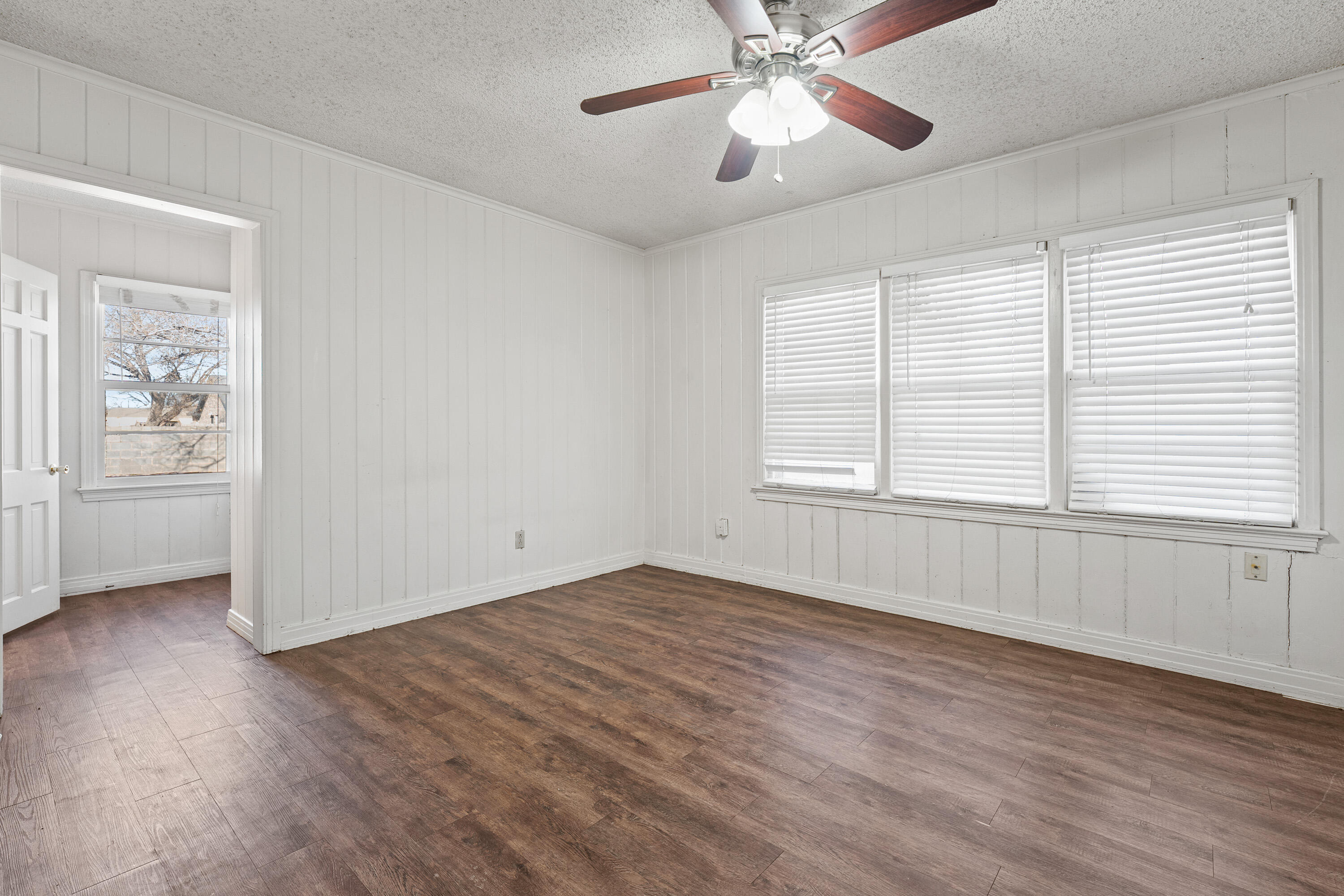 2216 30th Street Lubbock, TX 79411 - Photo 5 of 21 an empty room with wooden floor chandelier fan and windows