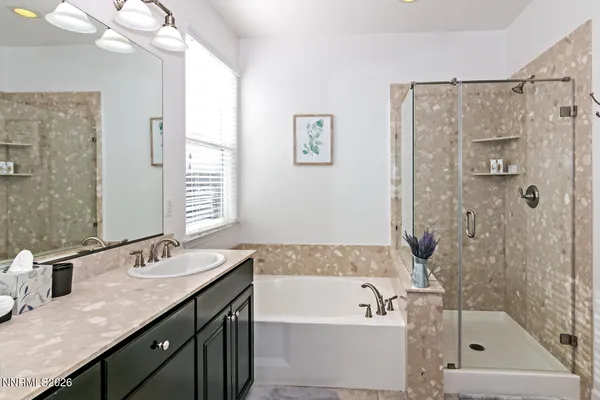 a bathroom with a granite countertop sink a mirror a bathtub and shower